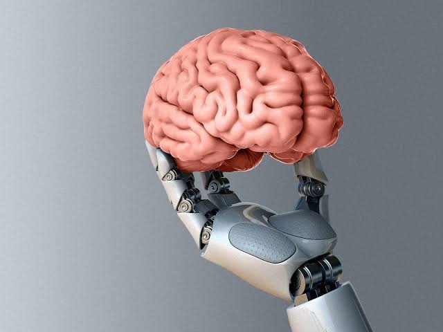 A robotic hand holding a model of a human brain
